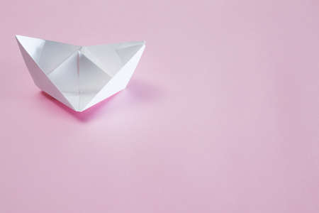 White paper handmade origami boat on the pink background. Copy space for your text. Theme of homemade toys for children.の写真素材