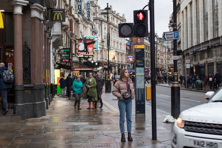LONDON, UK - March 20, 2020: A girl at a pedestrian crossing waits for the light to switchのeditorial素材