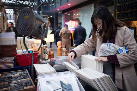 London, UK - 13 February, 2020 Spitalfields flea market. Girl picks records in big boxesのeditorial素材