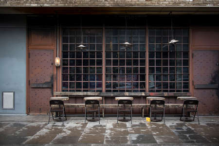 LONDON, UK - March 20, 2020: Hipster cafe, with windows on the floor, similar to a former factory with tables on the street in bad weatherのeditorial素材