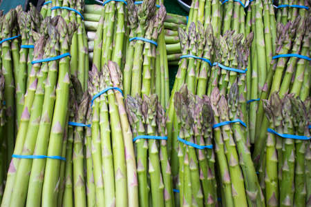 Bundled bundles of fresh asparagus on a counter for sale at a farmers marketの写真素材