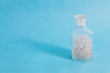 Bottle filled with dandelion fluffs on blue background. Concept. Copy spaceの写真素材