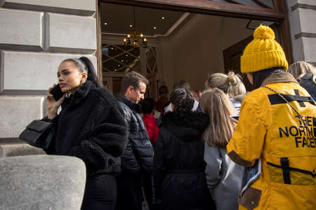 London, UK - 15 February, 2020, A girl with a ponytail in a black short faux fur coat is talking on...
