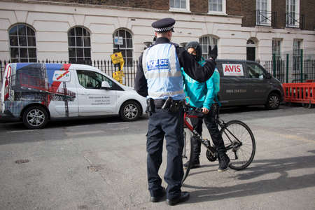 London, UK - 15 January, 2020, A police officer stopped a food delivery courier on a bicycle and checks documentsのeditorial素材