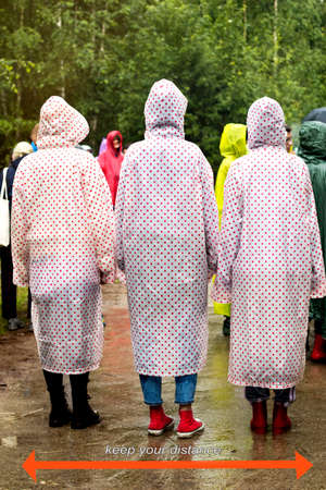White text is on a blurred photo with unrecognizable people in color raincoats go to the forest....