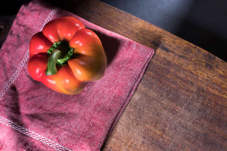 Red pepper on a craft napkin on a cutting board. Place for text on the dark backgroundの写真素材