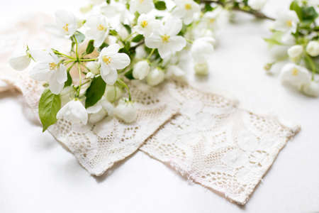 Lace with a blossoming apple tree branch on a stone surface of a table with reflections. Space for text.の写真素材