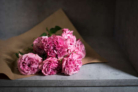 Freshly cutted pink terry roses on brown craft paper on a gray background.の写真素材