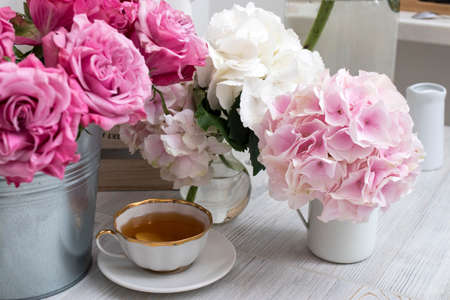 Bouquets of hydrangea, roses and a cup of tea between them. Pink colorの写真素材