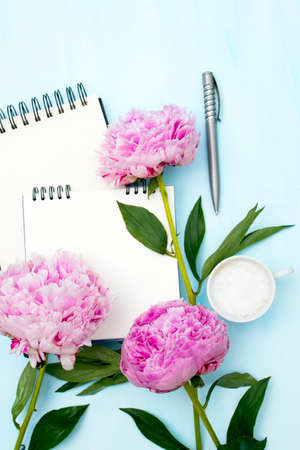 Three fresh blossoming pink peonies lie on a white open notebook. Space for text. To do list. Educational concept. Love letterの写真素材