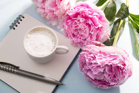 Three fresh blossoming pink peonies lie on a white open notebook. Space for text. To do list. Educational concept. Love letterの写真素材