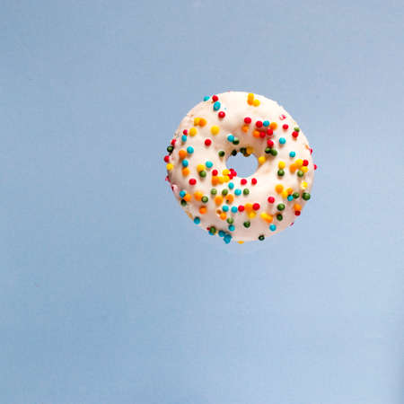 Delicious donut with icing and candy on a blue background. Square blue background.の写真素材