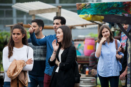London, UK - 17 July 2019, Nomadic Community Garden. Communal Garden Party. Group of friends wonder where to go, showing direction with hand.のeditorial素材