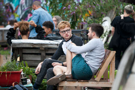 London, UK - 17 July 2019, Nomadic Community Garden. Communal Garden Party. Two men are sitting on...
