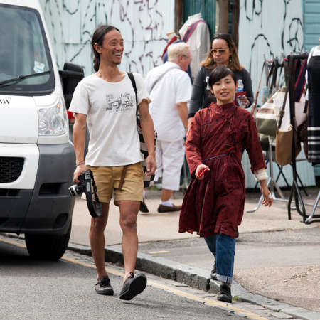 London, UK - 17 July 2019, Columbia Road Flower Market. A man in a white T-shirt and yellow shorts...