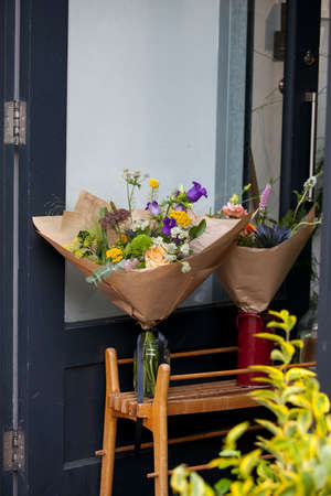 London, UK - 17 July 2019, Columbia Road Flower Market . Bouquets of flowers with bells wrapped in gray craft paper in jugs on a trolley in front of the store.のeditorial素材