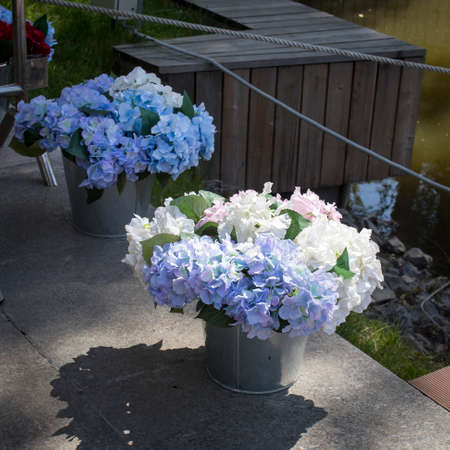 Artificial white and blue hydrangeas in aluminum buckets adorn the restaurant entrance. Decorationの写真素材
