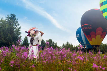 Pereslavl-Zalessky, Yaroslavl Region, Russia, - July 19, 2020: 19 - Aeronautics Festival Golden Ring. Girl dressed in vintage dress and hat posing against the background of balloons.のeditorial素材