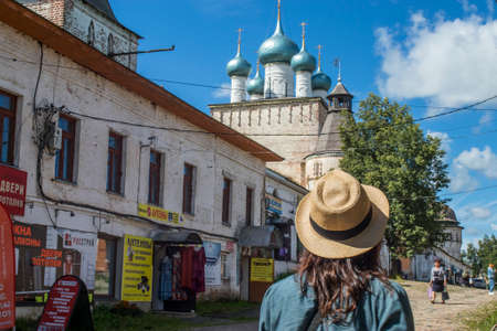 Borisoglebsky, Yaroslavl region, Russia, - 26 July 2020, Orthodox Boris and Gleb monastery. Vintage square at entrance. Back view of brunette girl with long hair in straw hat, green shirt.のeditorial素材