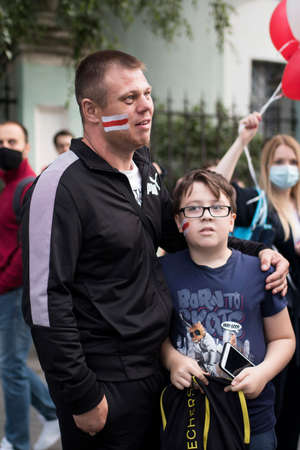 Moscow, Russia - 11 August 2020, demonstrators demand resignation of President Lukashenko in front of embassy of Belarus. Father and son are embracing. The Belarusian flag is painted on the cheeks.のeditorial素材