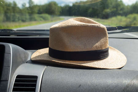 A straw hat lies in front of the front windshield in a car while traveling.の写真素材