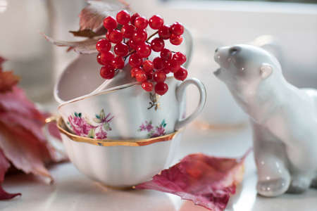 porcelain figurine of a polar bear with a viburnum branch in the cup on the windowsill.