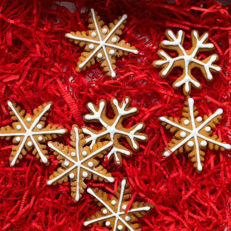 Square frame. Top above high angle closeup overhead view of nice christmas decoration. Gingerbread cookies in the form of snowflakes, arrows, stars and hearts in red wood shavingsの写真素材