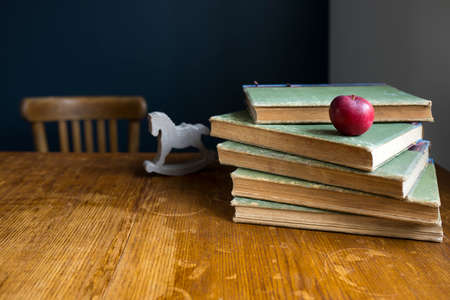 A stack of large, old, rag-bound books lie on a wooden table against a dark blue wall. Pen and notebook. Concept - back to school. Online training. Copy space. Select focus.の写真素材