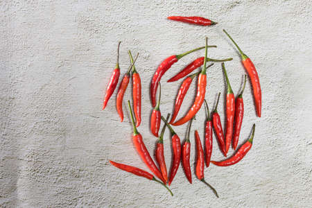 A lot of red hot miniature pepper lies on the concrete surface of the table. Copy space.の写真素材