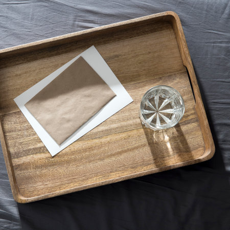 A glass of water and half a grapefruit on a wooden tray on a gray sheet on the bedの写真素材