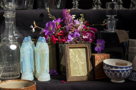 London, UK - 20 September 2020, Four crystal virgins of Mary, wildflowers bouquet, glass decanter, embroidery frame for sale at Spitalfields marketのeditorial素材