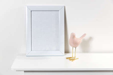 White photo frame with blank space .. Statuette of a pink bird. Scandinavian styleの写真素材