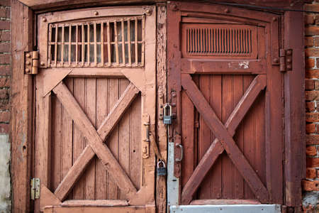 Old barn doors, with peeling paint, with two large metal locks on them. Patternの写真素材
