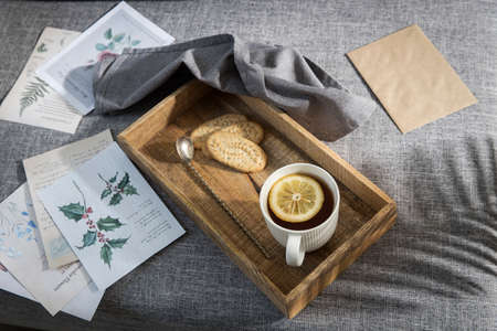 A white cup of tea with lemon, a long cupronickel spoon with a twisted handle and a saucer with...