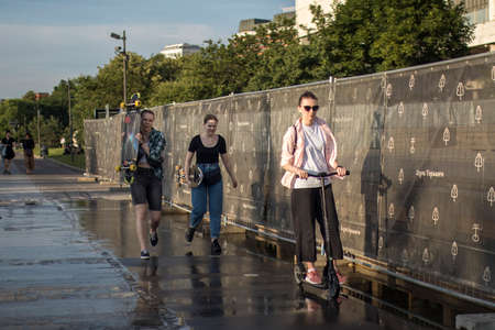 Moscow, Russia - 21 June 2021, Three girls with skateboards walking down the street