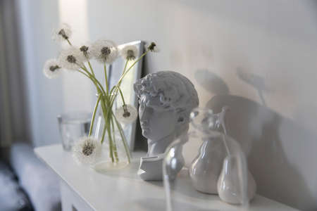 A bunch of fluffy dandelions in a chemical flask, an empty photo frame, a cup of espresso coffee,...