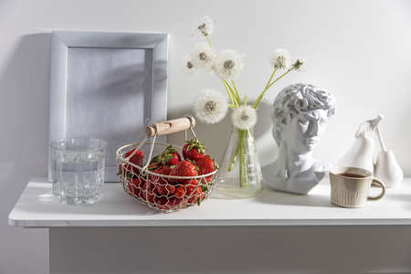 A bunch of fluffy dandelions in a chemical flask, an empty photo frame, a cup of espresso coffee,...