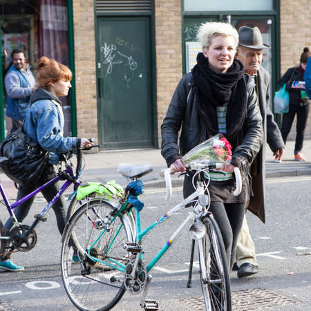 London, UK - September 2019, People with bicycles, Short-haired blonde girl with a bicycle and an elderly man with a cane cross the road on a pedestrian crossingのeditorial素材