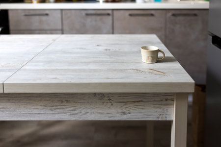 Small beige corrugated coffee empty cup eat on wooden table in the beige kitchen interior