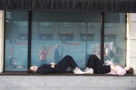 Moscow, Russia - 31 August, 2021, Two girls lie on the windowsill of a large window, resting....