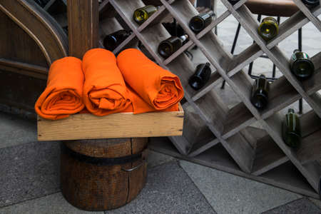 Orange fleece blankets rolled into rolls against the background of a wine cabinet with bottles in a cafeの写真素材