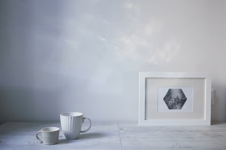 Scandinavian style. Interior Design. A white cup of different size, a frame for a photo are on the table. Empty space for textの写真素材