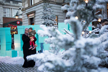 London, UK - 20 November 2020, People posing against the backdrop of a snow-covered Christmas tree at Covent Gardenのeditorial素材