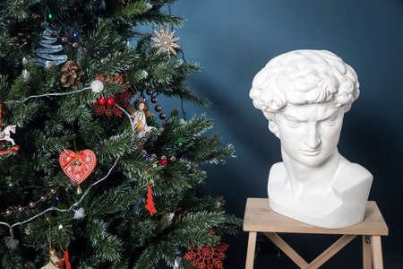 A plaster cast of David's head stand on a stool in a dark blue roomの写真素材