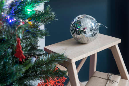 Disco ball on a stool near a Christmas tree as an interior decorationの写真素材