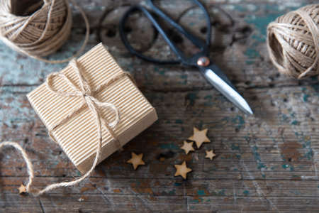 Two skeins of craft thread, scissors, two packed boxes, wooden stars lie on a wooden tableの写真素材