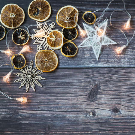Dried orange slices, thread stars, cut snowflakes, garland on a wooden table. Place for your text. Shooting from above. Copy spaceの写真素材