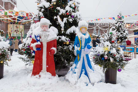 Moscow, Russia - 20 December 2021, Figures of Santa Claus and Snow Maiden as decoration of the fair near Gum. A large fir tree decorated with toys, covered with snow. GUM-fair on Red Square, Christmas marketのeditorial素材