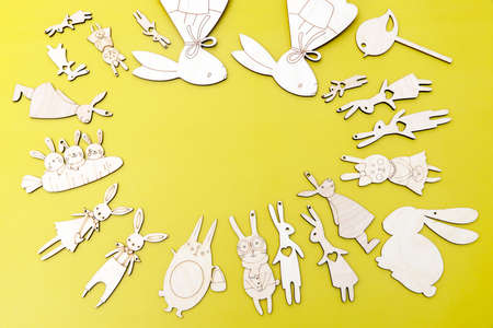 Funny figurines of hares carved from plywood forming a frame for the inscription. Easter concept.Yellow backgroundの写真素材