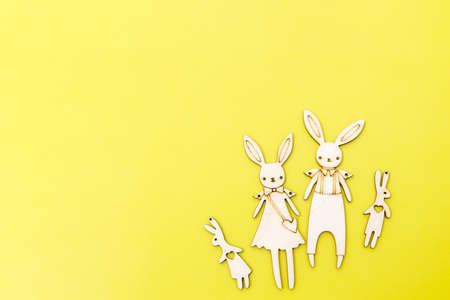 Family of funny hares cut out of plywood are on the yellow background. card design. copyspace. Place for textの写真素材